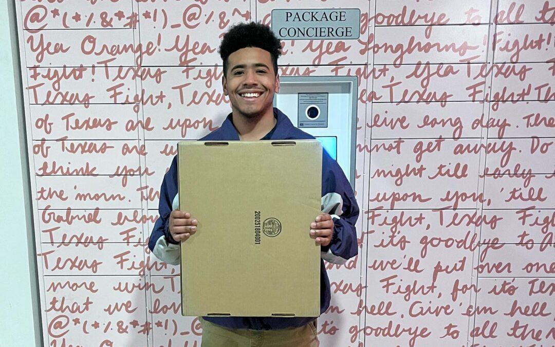 Smiling student holding package in front of smart package locker